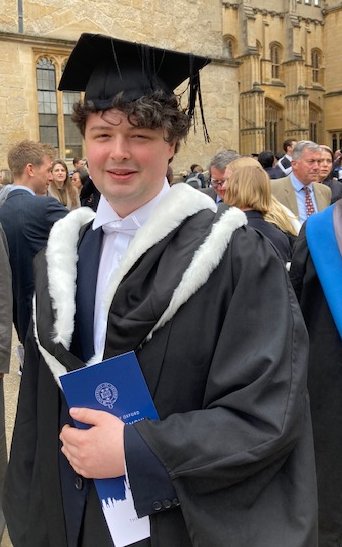 Photo of me, Finn, in the cap, hood, and gown of an Oxford Bachelor of Arts, outside the Bodleian Library